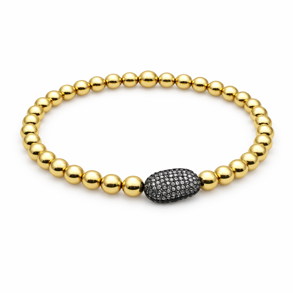 Gold beaded bracelet with a black diamond-studded bead on a white background
