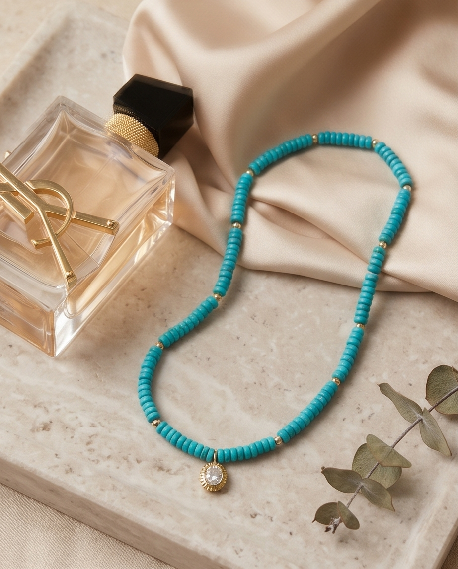Turquoise and gold filled stretch beaded necklace with CZ pendant beside perfume bottle on stone tray — Stacked by Jayneebell