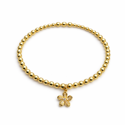 Gold beaded bracelet with a flower charm on a white background
