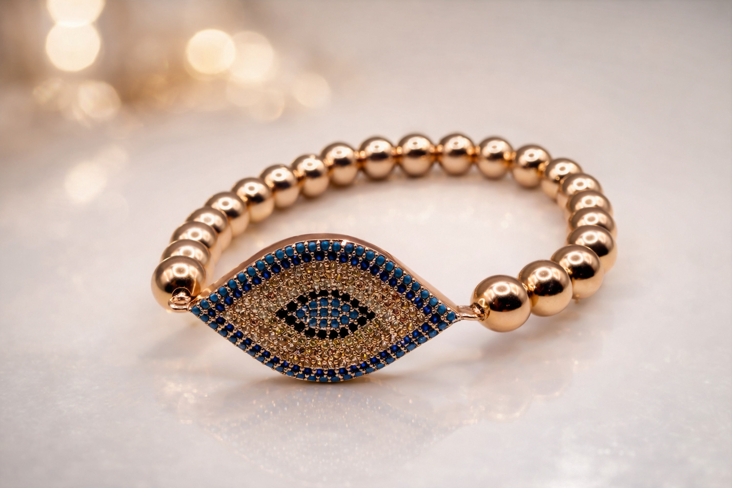 Gold beaded bracelet with an eye design on a light background