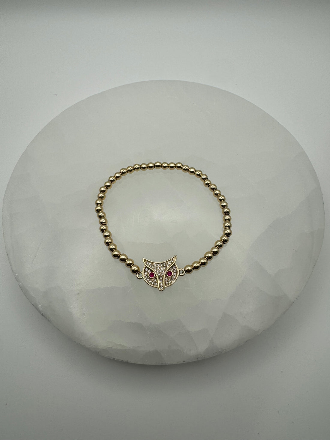 old plated 4mm stretch beaded bracelet with fox owl flat charm on stone surface