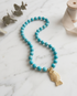 atural turquoise beaded necklace with gold fish pendant on marble — The Turquoise Tide by Stacked by Jayneebell