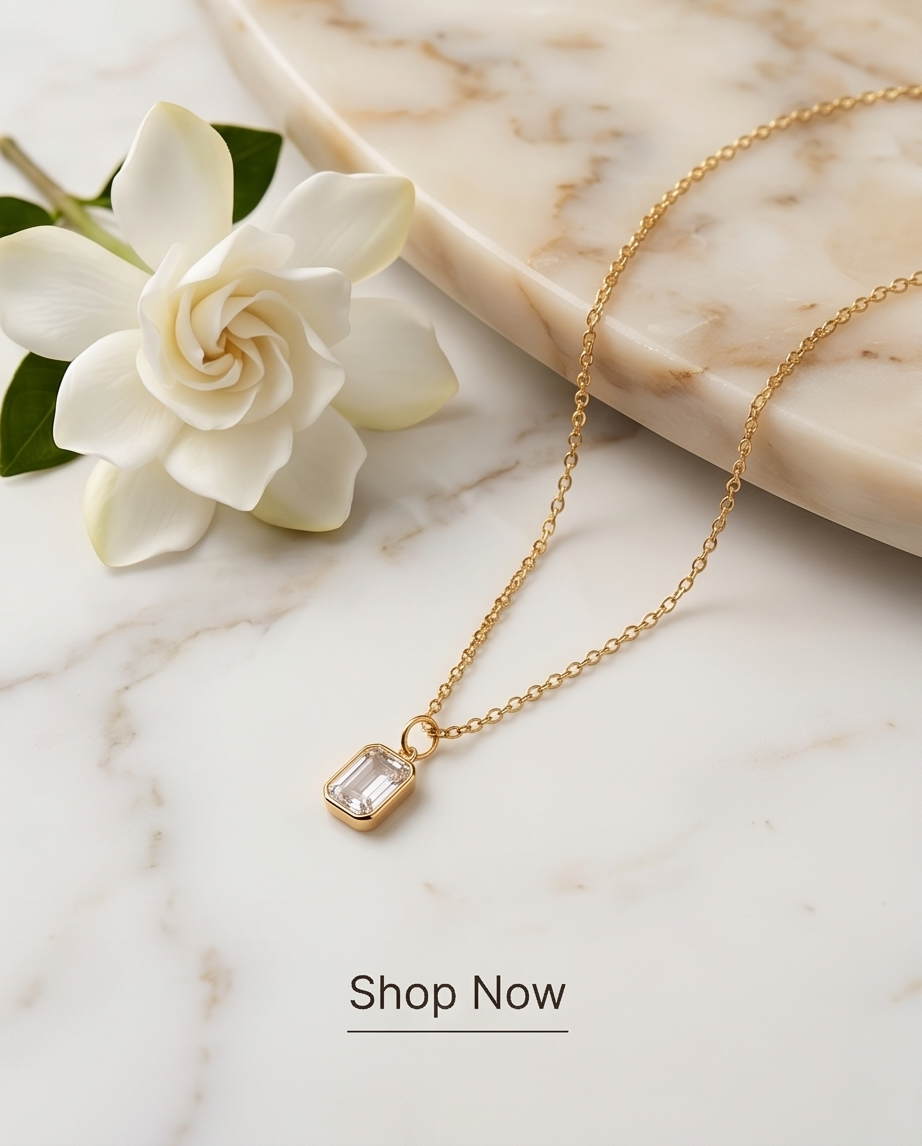 2 carat emerald cut lab diamond pendant on 14k gold filled chain on cream white marble counter with a flower  — The Luminaire by Stacked by Jayneebell