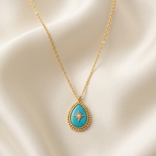 True North turquoise teardrop pendant gold chain necklace on cream fabric, Stacked by Jayneebell