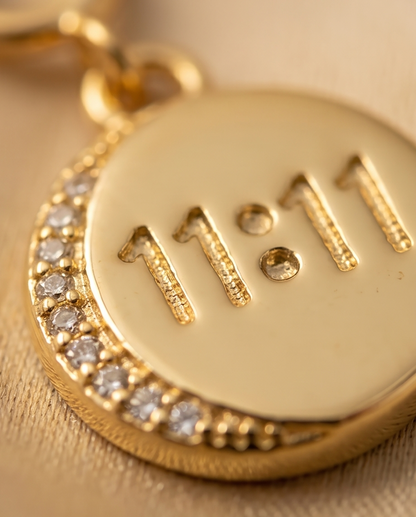 Close up of embossed 11:11 lettering and pave CZ crescent arc on gold filled coin charm — Stacked by Jayneebell