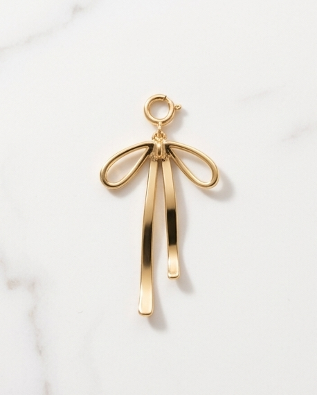 Gold filled open wire ribbon bow charm with long trailing tails and spring ring clasp on marble — Stacked by Jayneebell