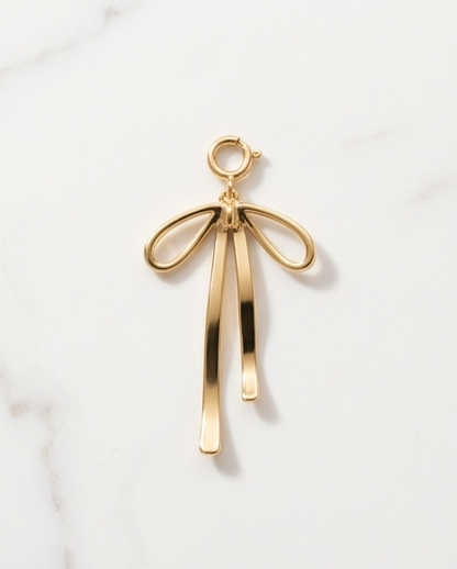 Gold filled open wire ribbon bow charm with long trailing tails and spring ring clasp on marble — Stacked by Jayneebell