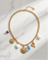 Close-up detail of Endless Summer gold PVD mixed charm necklace with sacred heart, blue crystal and white heart charms, Stacked by Jayneebell