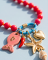 Close-up detail of The Catch coral charm cluster with fish, chili pepper, starfish and heart charms, Stacked by Jayneebell