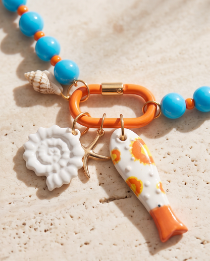 Close-up detail of The Catch tide charm cluster with ceramic shell, starfish and fish charms, Stacked by Jayneebell