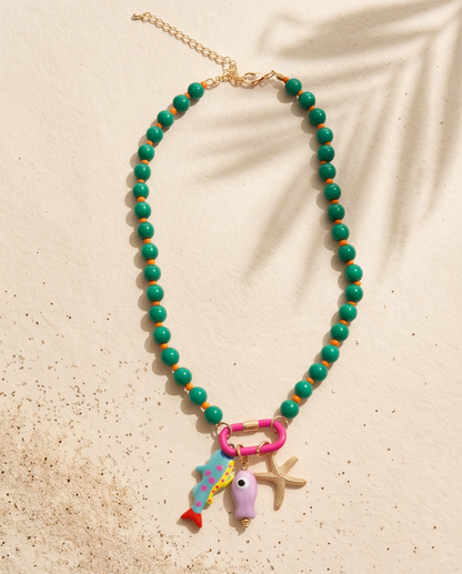 The Catch mermaid colorway green beaded charm necklace with pink carabiner on sand, Stacked by Jayneebell
