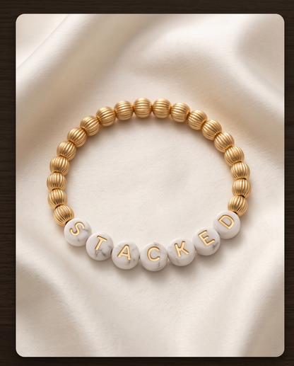 Custom mother of pearl and gold filled word bracelet spelling STACKED on cream satin — Just Sayin&